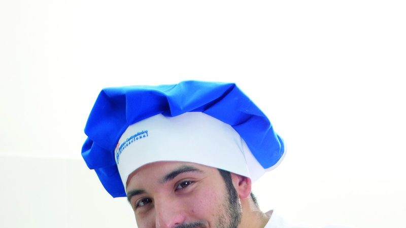 Panadero trabajando una masa sobre una mesa de producción