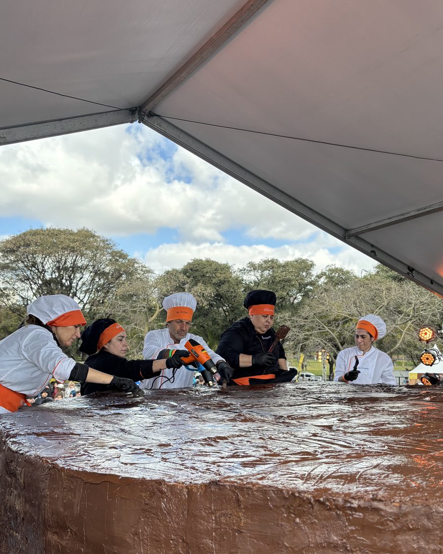 Pasteleros del IGI trabajando la cobertura de chocolate del alfajor gigante en el evento