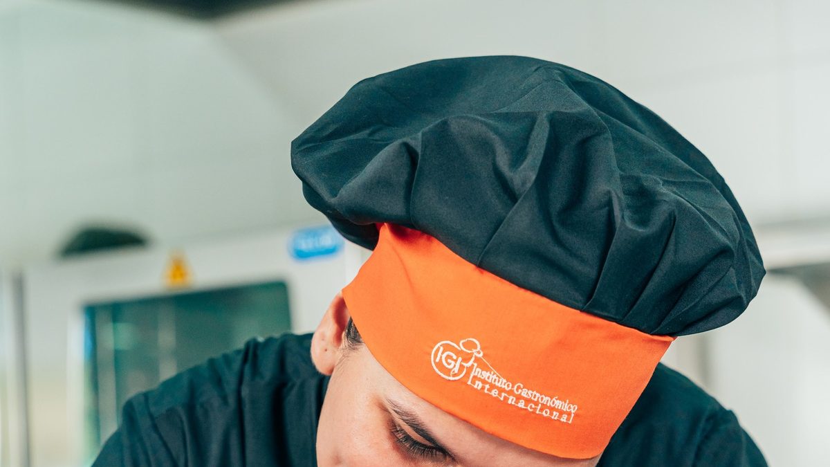 Docente observando el trabajo práctico de estudiantes de gastronomía
