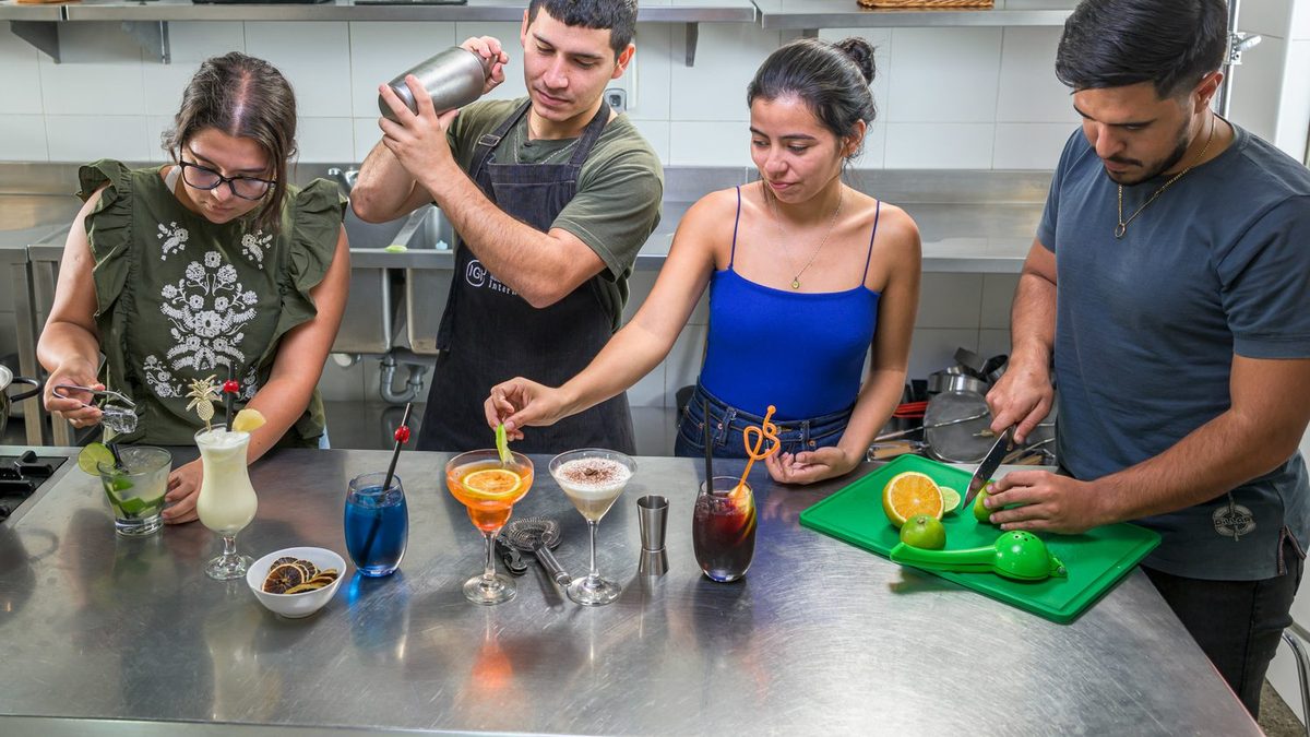 Estudiantes del curso de Bartender de IGI preparando una tanda de cócteles sobre la mesada de práctica