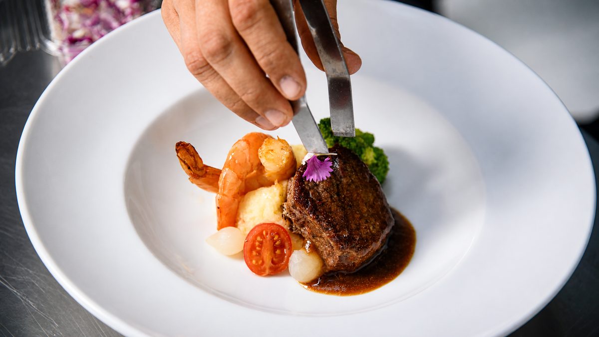 Emplatado de una preparación gastronómica con carne, vegetales y salsa
