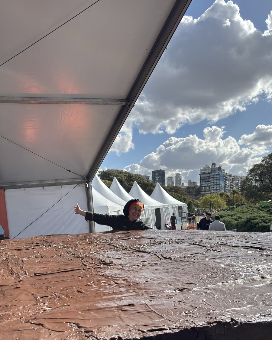 Vista de la superficie terminada del alfajor gigante, con una persona apoyada sobre el borde para dar escala