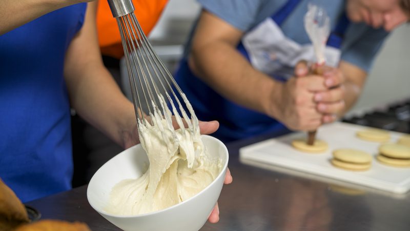 Batido de crema con batidor de alambre durante una clase de pastelería de IGI