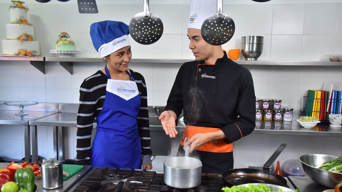 Chef instructor de IGI y alumna trabajando sobre el fuego en una clase de cocina