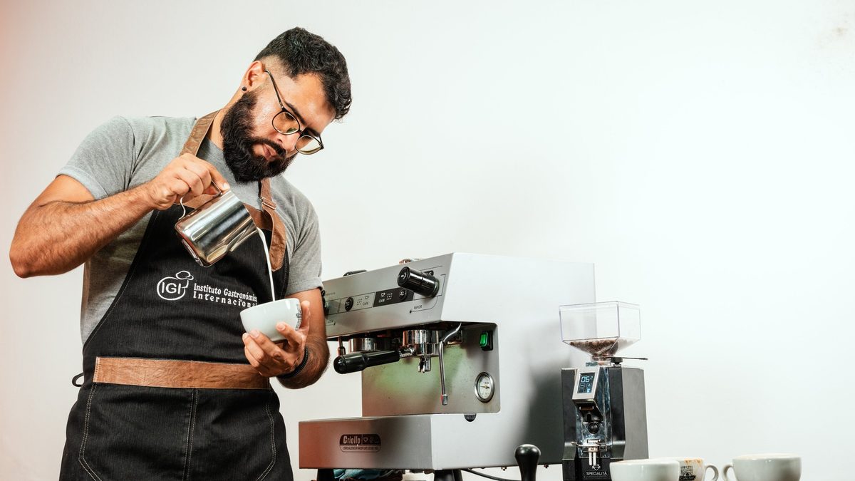 Barista de IGI realizando latte art junto a una máquina de espresso
