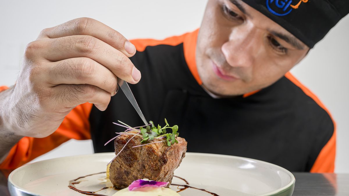 Chef colocando brotes sobre un plato durante el emplatado