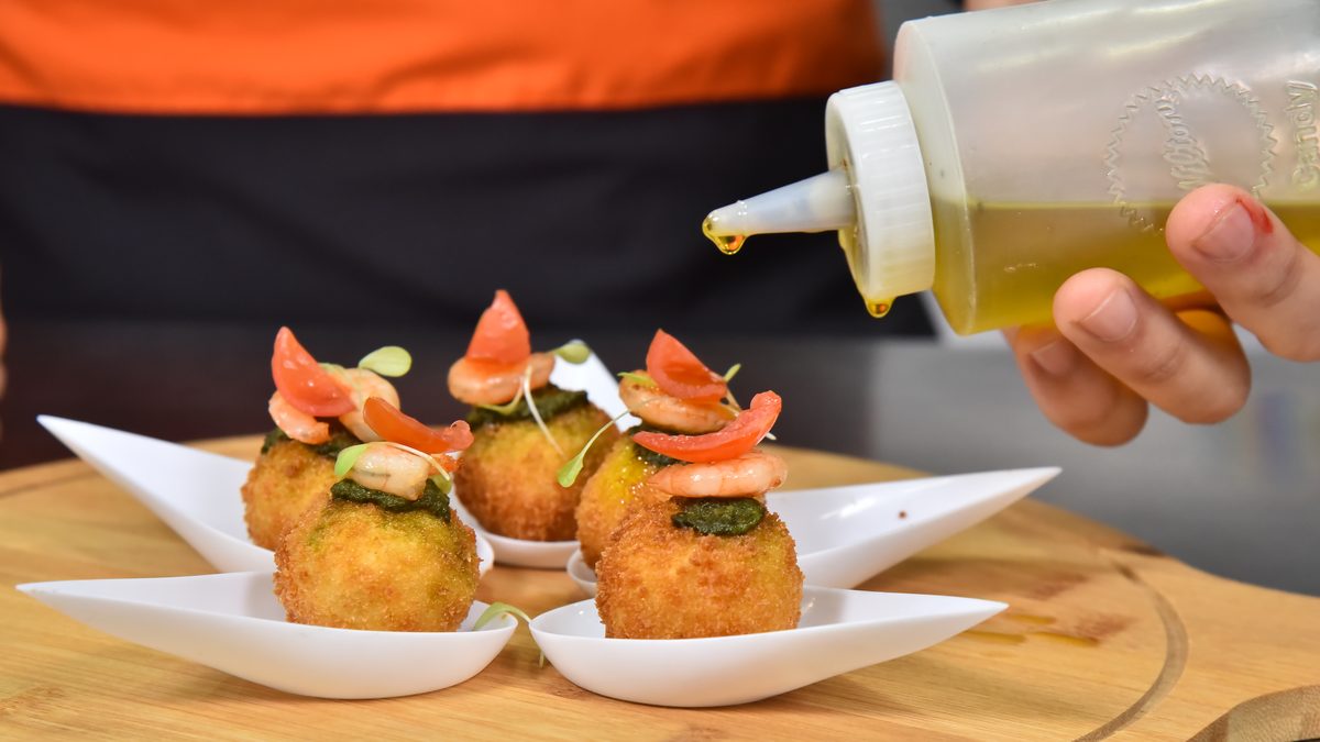 Chef de IGI terminando bocados emplatados con un hilo de aceite de oliva