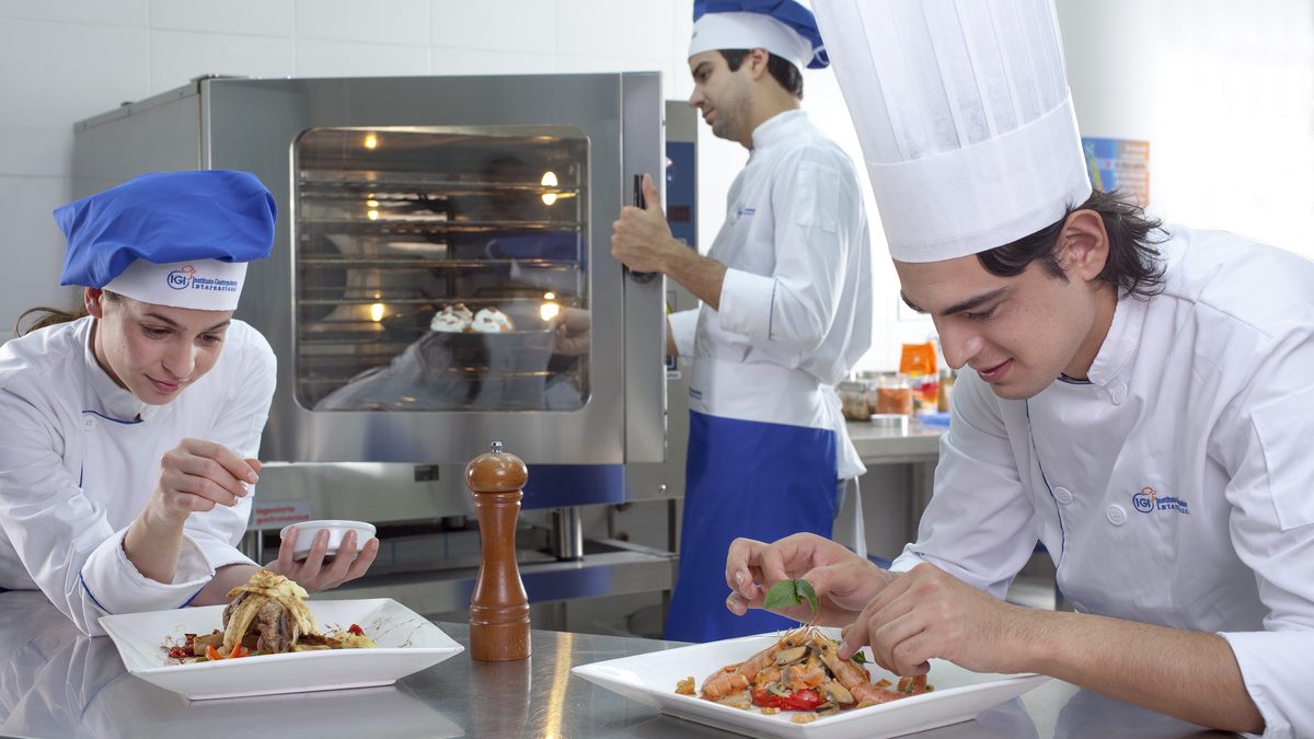 Profesional adulto preparando y presentando un plato en una cocina de IGI