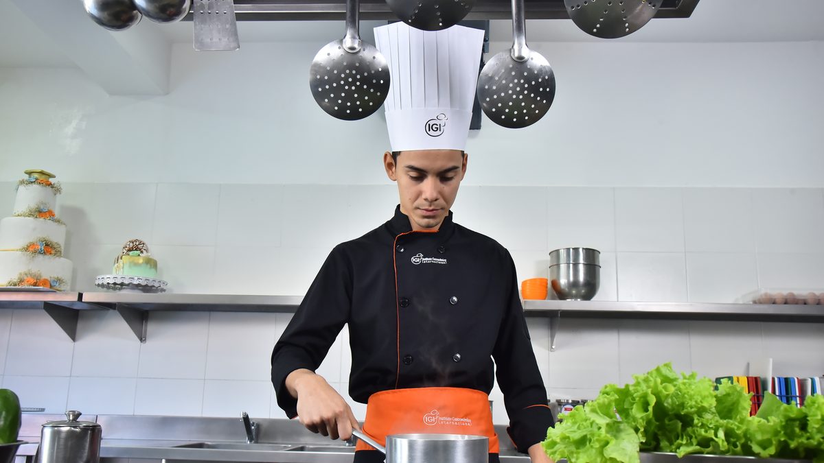 Chef de IGI cocinando en una olla grande sobre la cocina industrial de la escuela