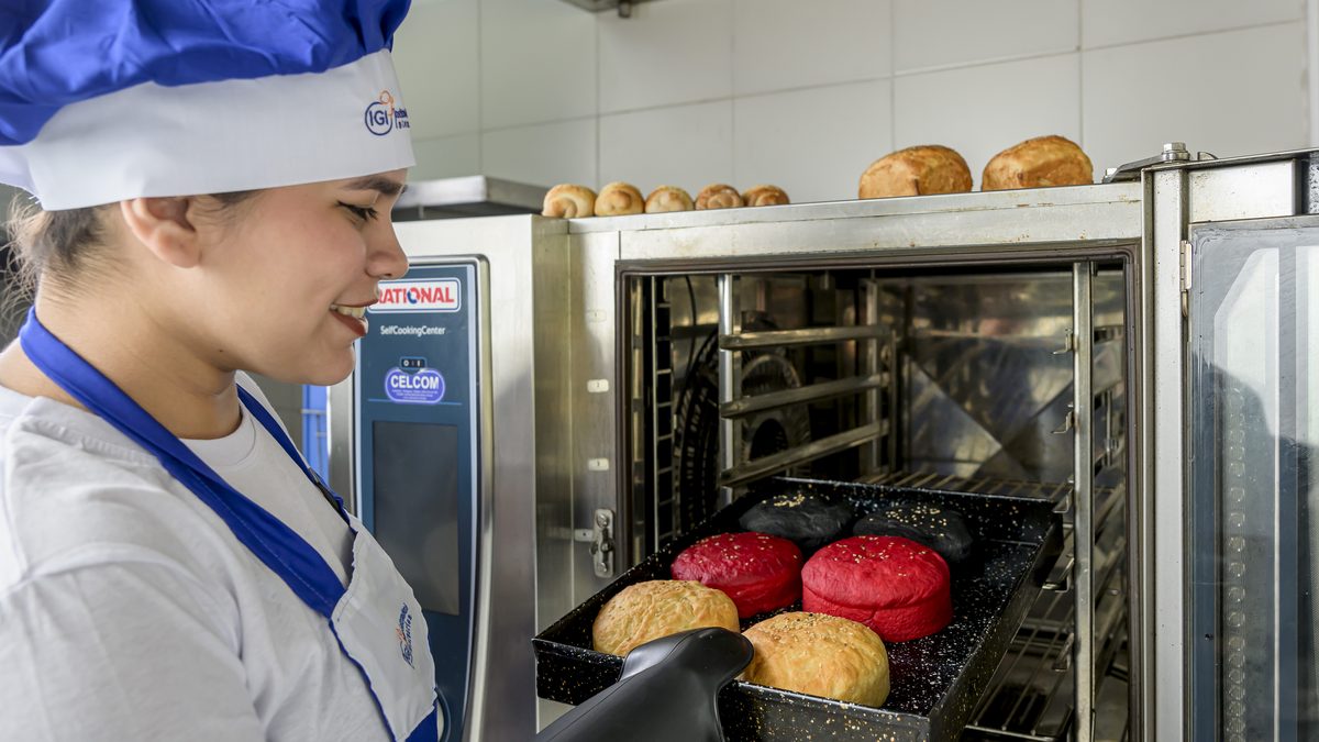 Estudiante controlando un horno profesional durante una práctica gastronómica