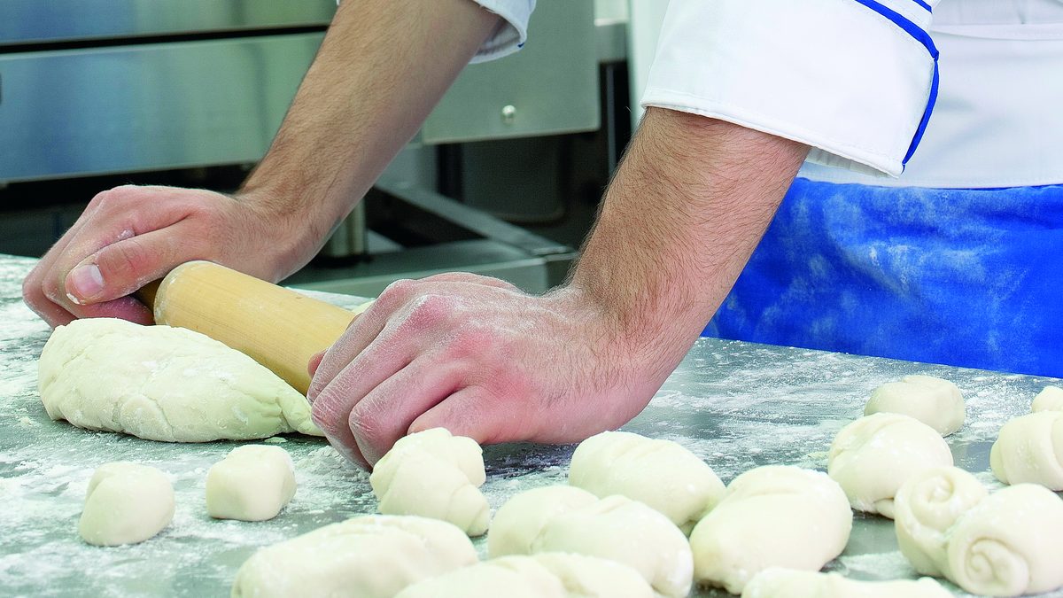 Manos de un estudiante de panadería de IGI trabajando masa sobre la mesada