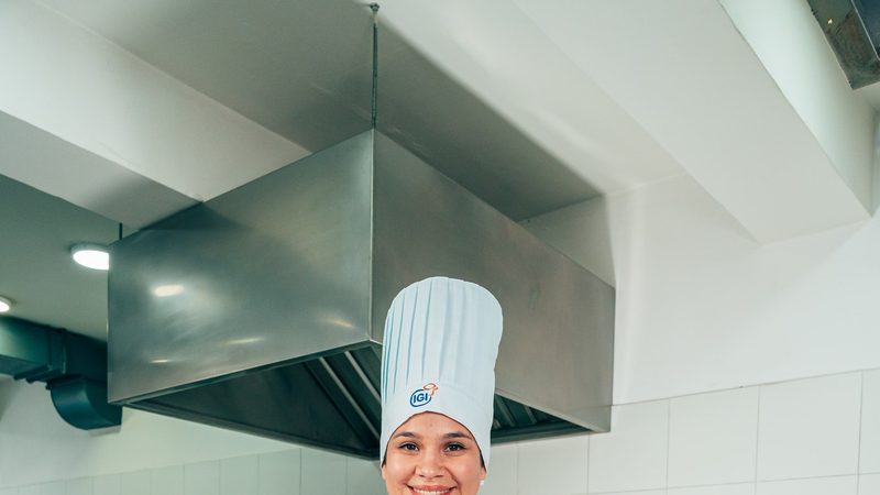 Pastelera pesando y trabajando ingredientes con precisión en una cocina de IGI