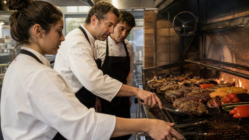 Cocinero trabajando frente a una parrilla encendida