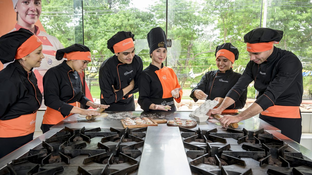 Grupo de alumnos de IGI amasando sobre la mesada durante una clase práctica de pastas