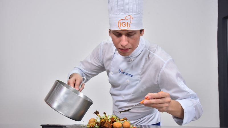 Chef sirviendo salsa sobre un plato terminado
