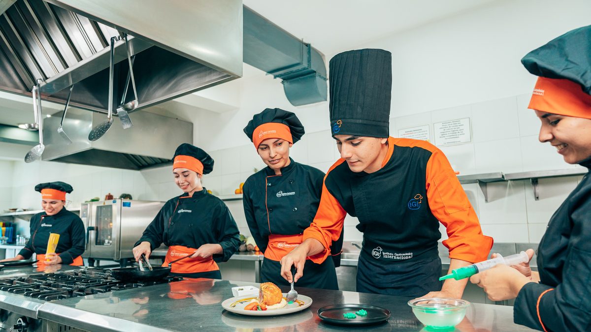 Grupo de alumnos de IGI emplatando junto al chef instructor en una clase práctica de cocina